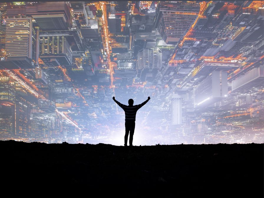 Silhouette of man standing with arms raised with top-down view of buildings in the sky